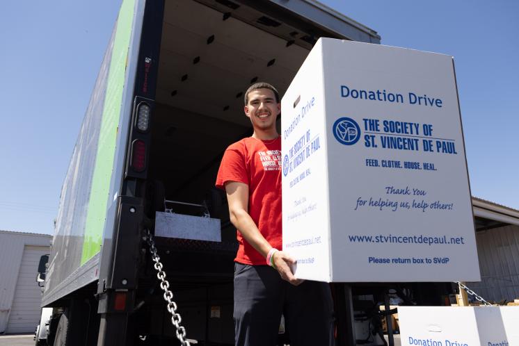 food-drives Man holding a food drive donation box on the back of on SVdP truck