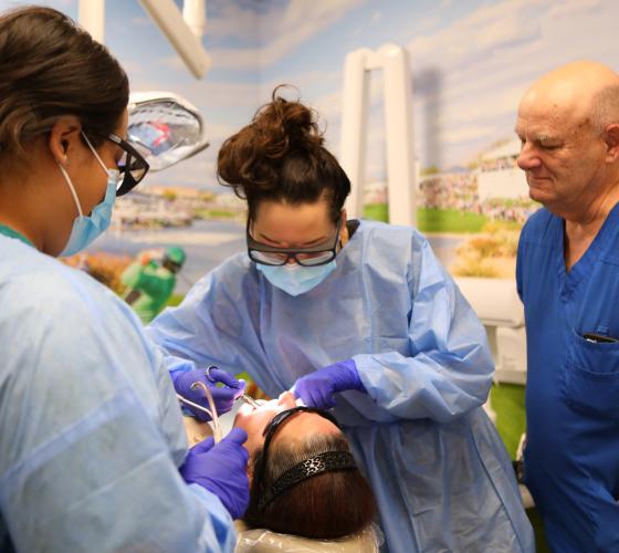 Dental Clinic Header Three dentists working on a patient