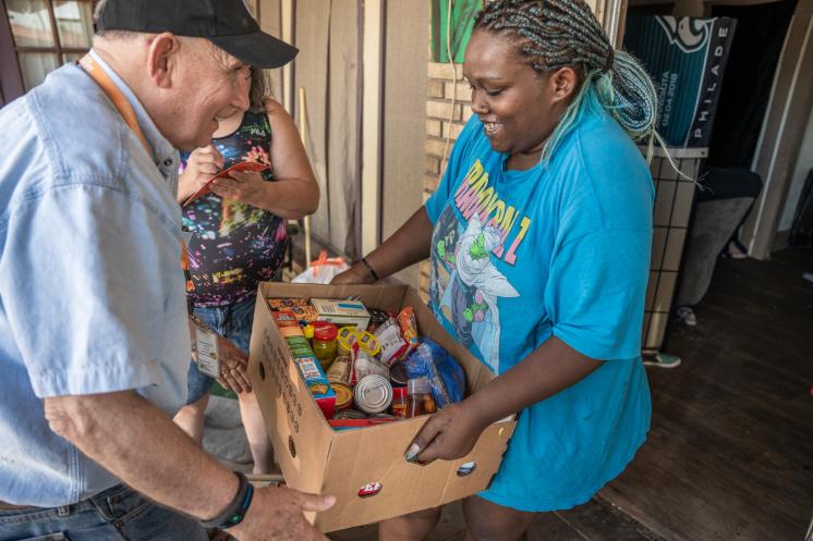 food-box-delivery Older man handing a woman a box of food